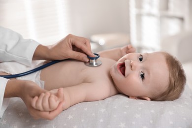 Photo of Pediatrician examining little child with stethoscope in clinic, closeup. Checking baby's health