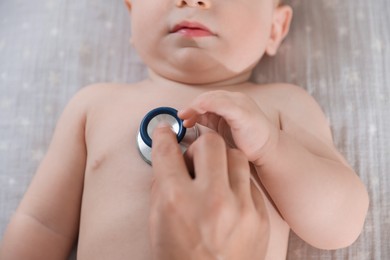 Photo of Pediatrician examining little child with stethoscope in clinic, closeup. Checking baby's health