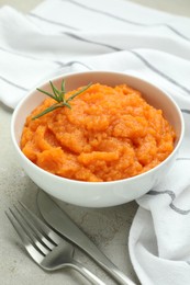 Photo of Tasty mashed sweet potato with rosemary in bowl served on grey textured table, closeup