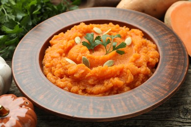 Photo of Tasty mashed sweet potato with pumpkin seeds and parsley in bowl on table, closeup