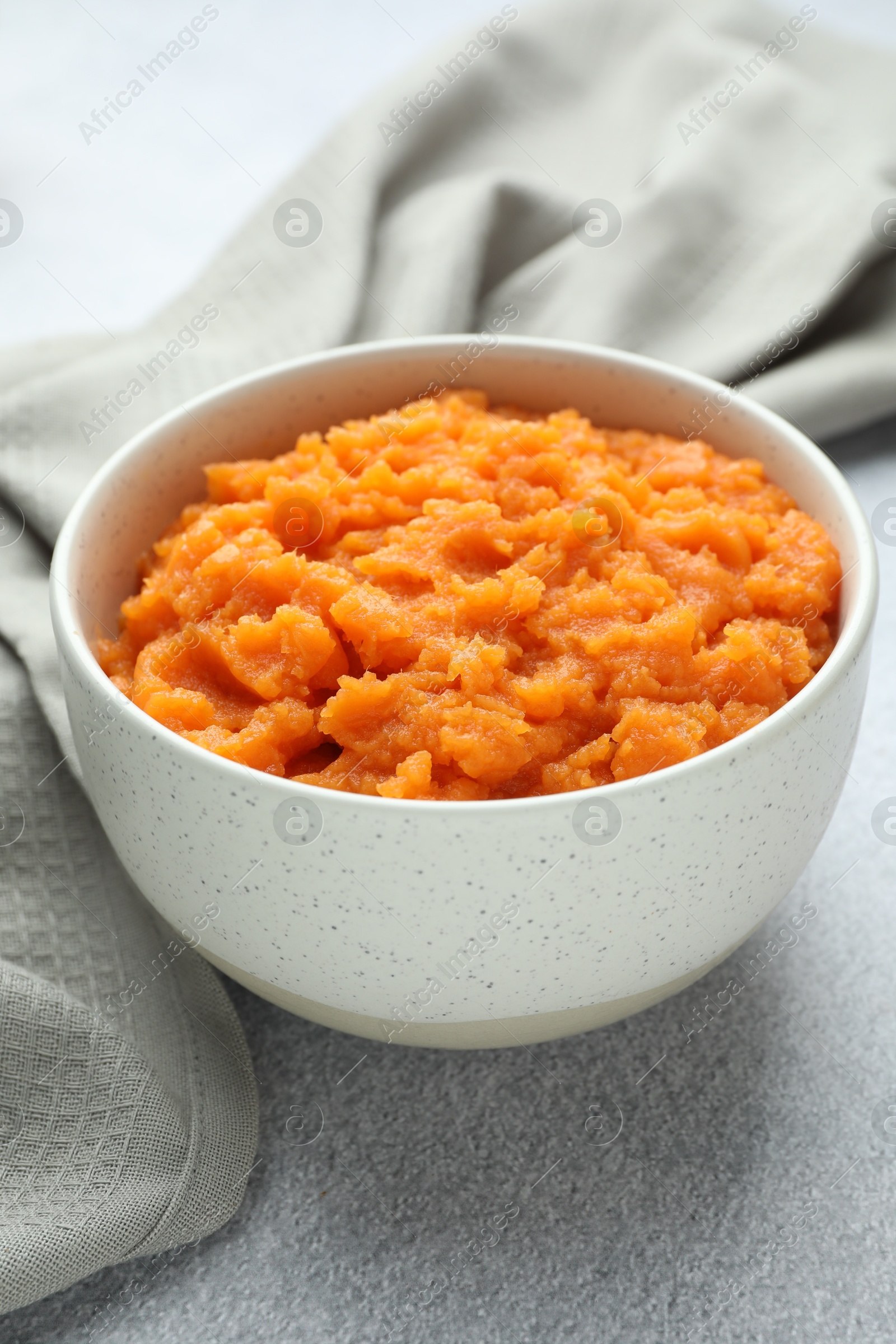 Photo of Tasty mashed sweet potato in bowl on gray table, closeup