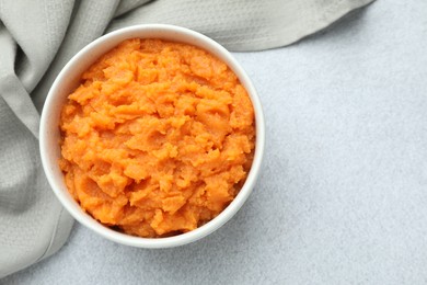 Photo of Tasty mashed sweet potato in bowl on gray table, top view. Space for text