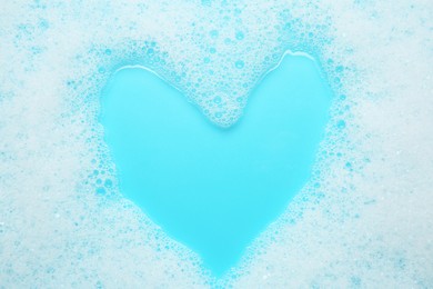 Photo of Washing laundry. White foam with bubbles on light blue background, top view