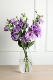 Vase with beautiful eustoma flowers on wooden table