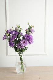 Vase with beautiful eustoma flowers on wooden table