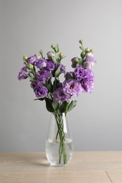 Vase with beautiful eustoma flowers on wooden table