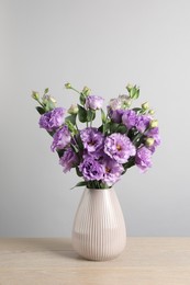 Vase with beautiful eustoma flowers on wooden table