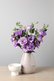 Photo of Vase with beautiful eustoma flowers on wooden table