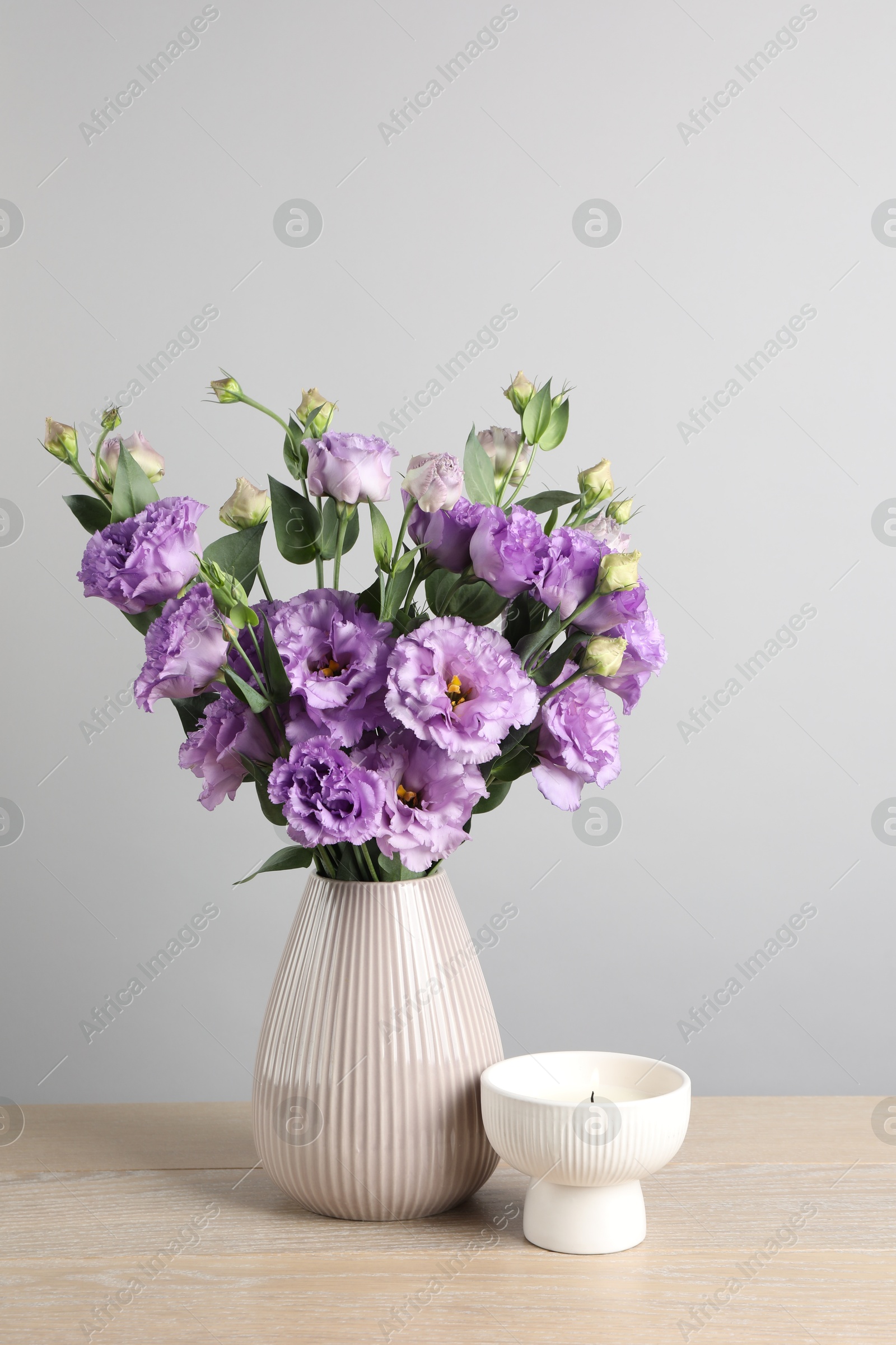 Photo of Vase with beautiful eustoma flowers on wooden table