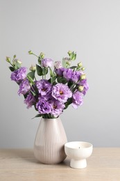 Vase with beautiful eustoma flowers on wooden table