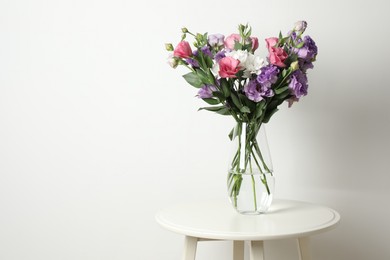 Vase with beautiful eustoma flowers on white table, space for text