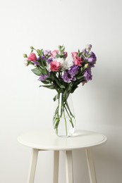 Photo of Vase with beautiful eustoma flowers on white table