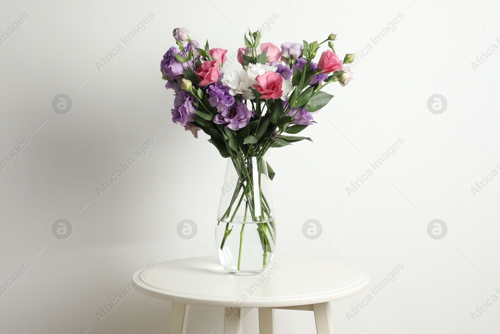 Photo of Vase with beautiful eustoma flowers on white table