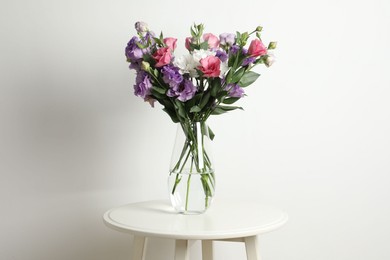 Vase with beautiful eustoma flowers on white table