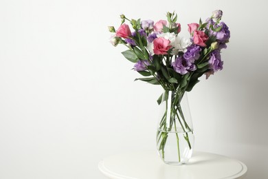 Photo of Vase with beautiful eustoma flowers on white table, space for text