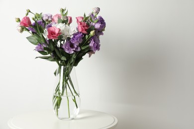 Vase with beautiful eustoma flowers on white table, space for text