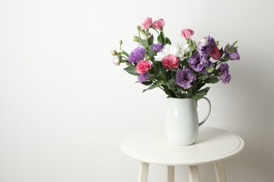 Vase with beautiful eustoma flowers on white table, space for text