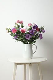 Vase with beautiful eustoma flowers on white table