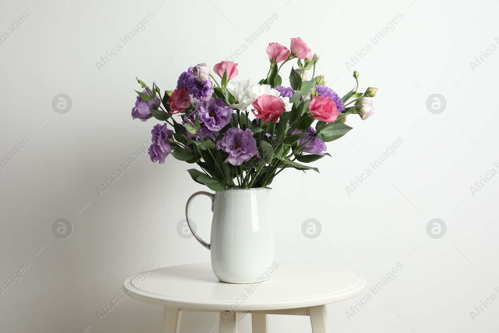 Photo of Vase with beautiful eustoma flowers on white table