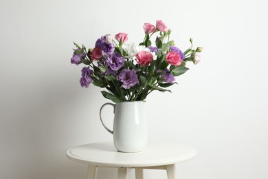 Vase with beautiful eustoma flowers on white table