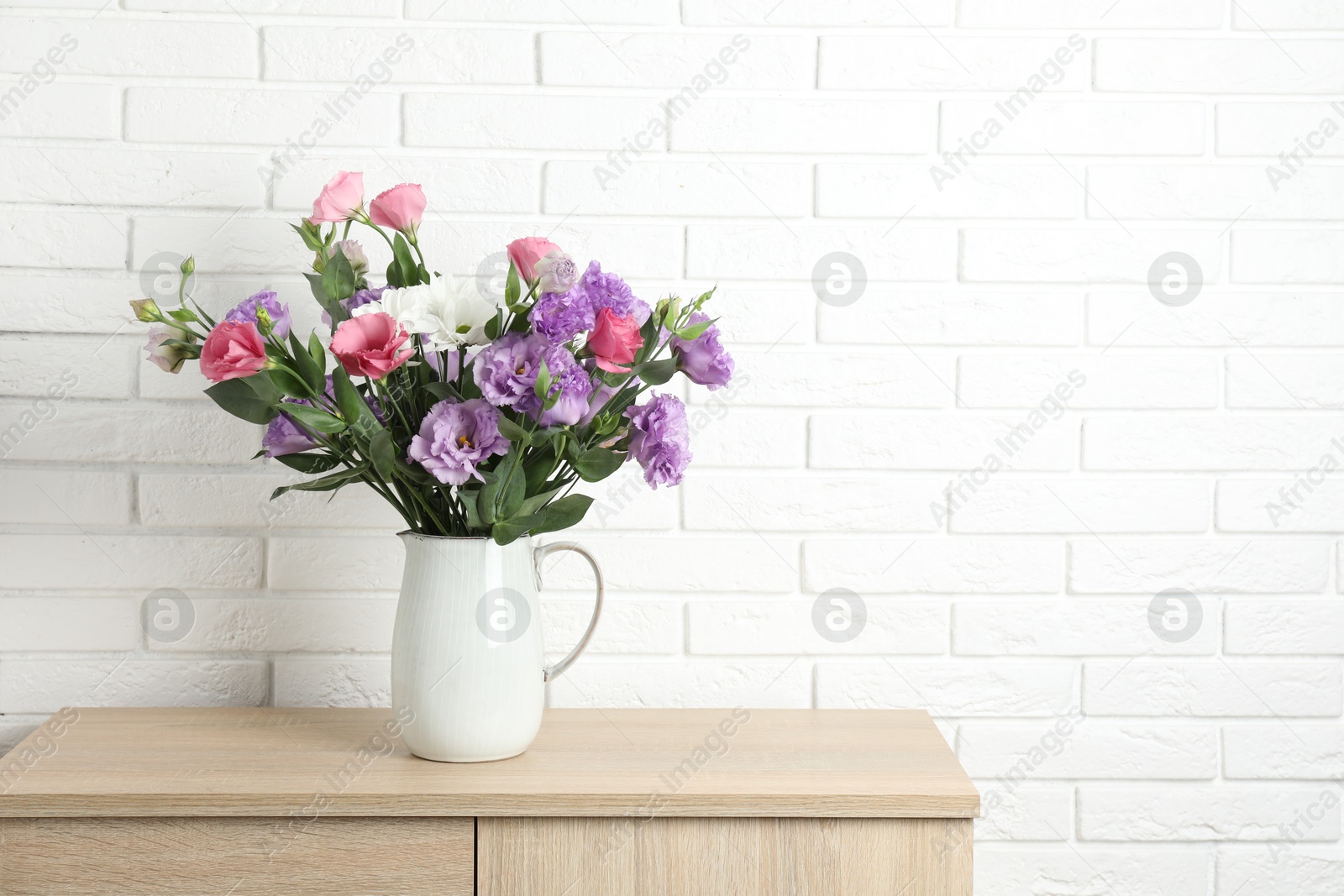 Photo of Vase with beautiful eustoma flowers on wooden chest of drawers, space for text