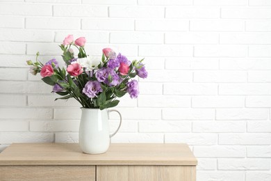 Vase with beautiful eustoma flowers on wooden chest of drawers, space for text