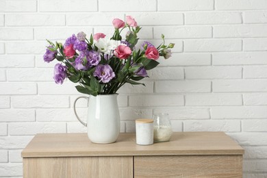 Photo of Vase with beautiful eustoma flowers on wooden chest of drawers