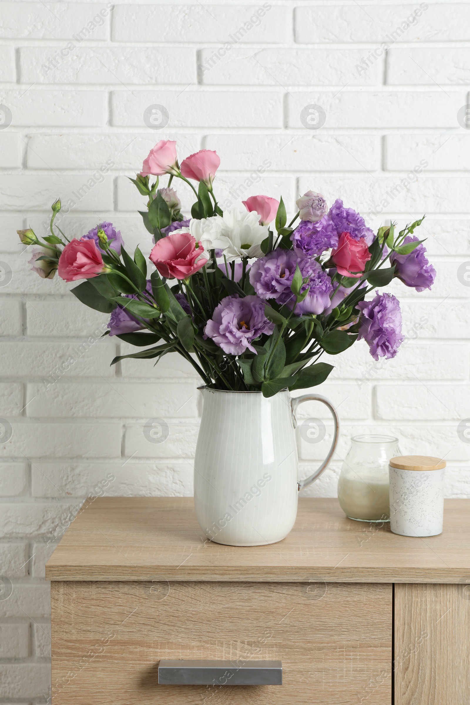 Photo of Vase with beautiful eustoma flowers on wooden chest of drawers