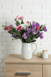 Vase with beautiful eustoma flowers on wooden chest of drawers