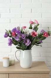 Vase with beautiful eustoma flowers on wooden chest of drawers