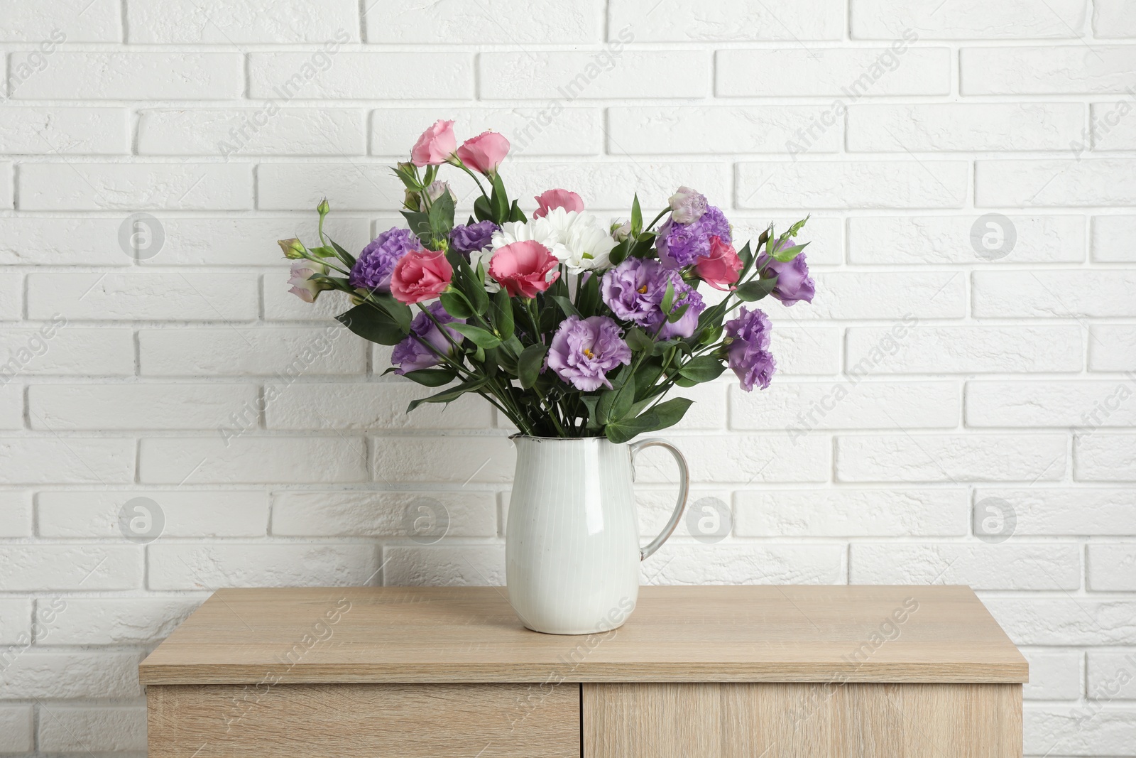 Photo of Vase with beautiful eustoma flowers on wooden chest of drawers