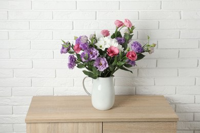 Photo of Vase with beautiful eustoma flowers on wooden chest of drawers