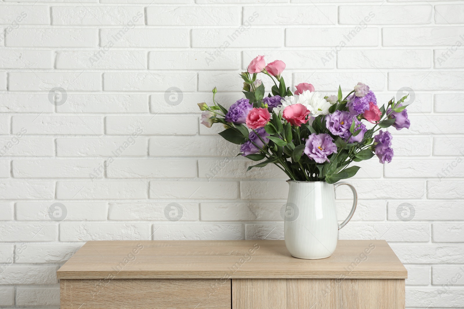 Photo of Vase with beautiful eustoma flowers on wooden chest of drawers, space for text