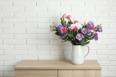 Vase with beautiful eustoma flowers on wooden chest of drawers, space for text