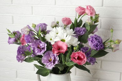 Photo of Vase with beautiful eustoma flowers near white brick wall, closeup