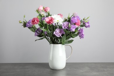 Vase with beautiful eustoma flowers on grey table