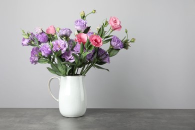 Vase with beautiful eustoma flowers on grey table, space for text