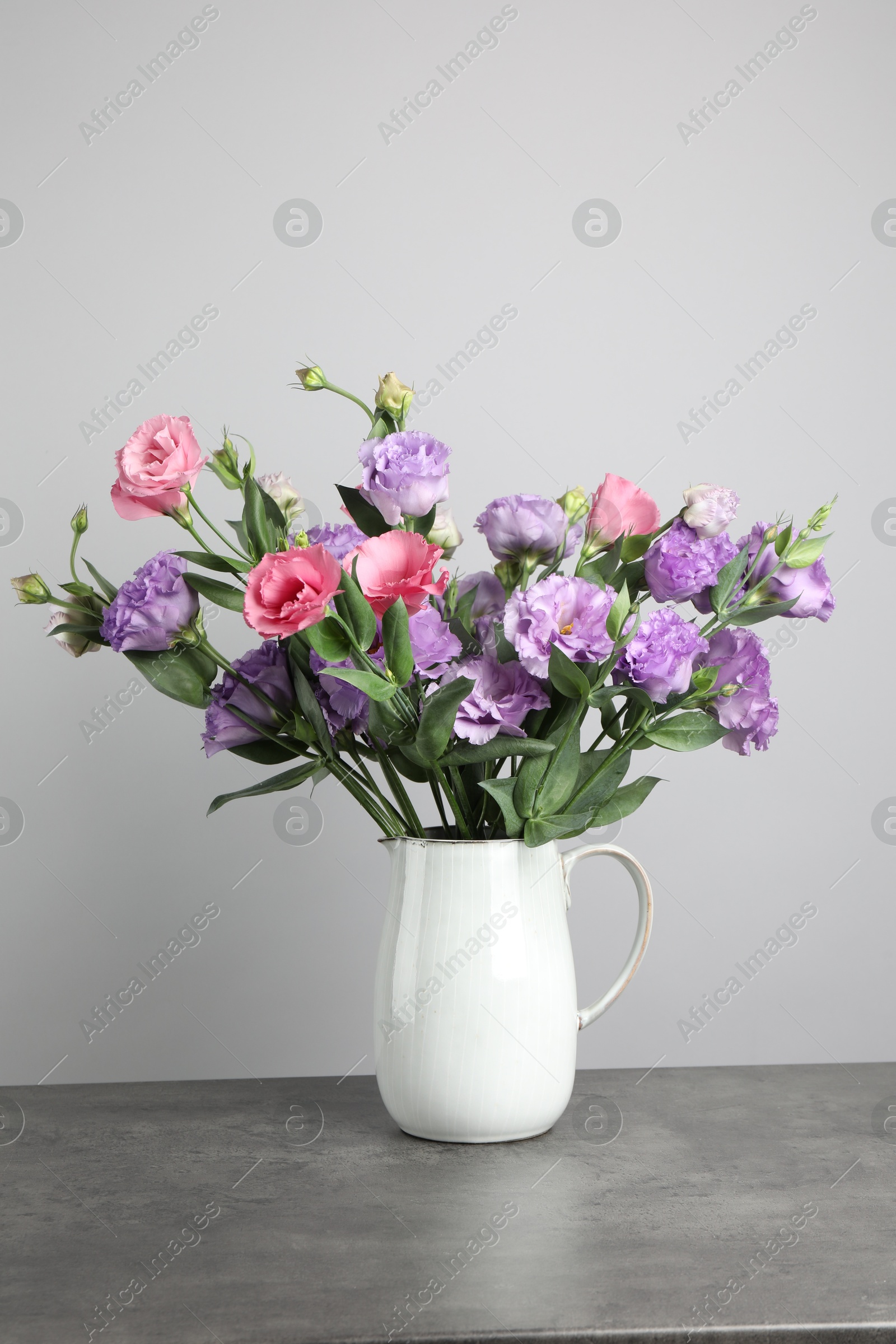 Photo of Vase with beautiful eustoma flowers on grey table