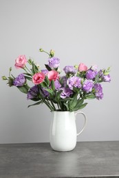 Vase with beautiful eustoma flowers on grey table