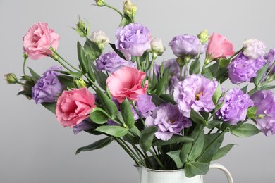 Vase with beautiful eustoma flowers near light grey wall, closeup