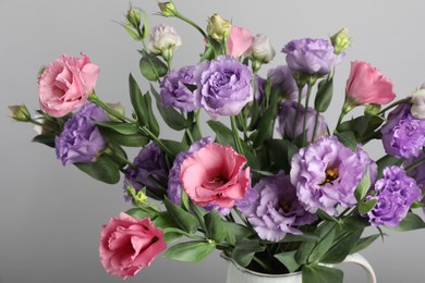 Vase with beautiful eustoma flowers near light grey wall, closeup