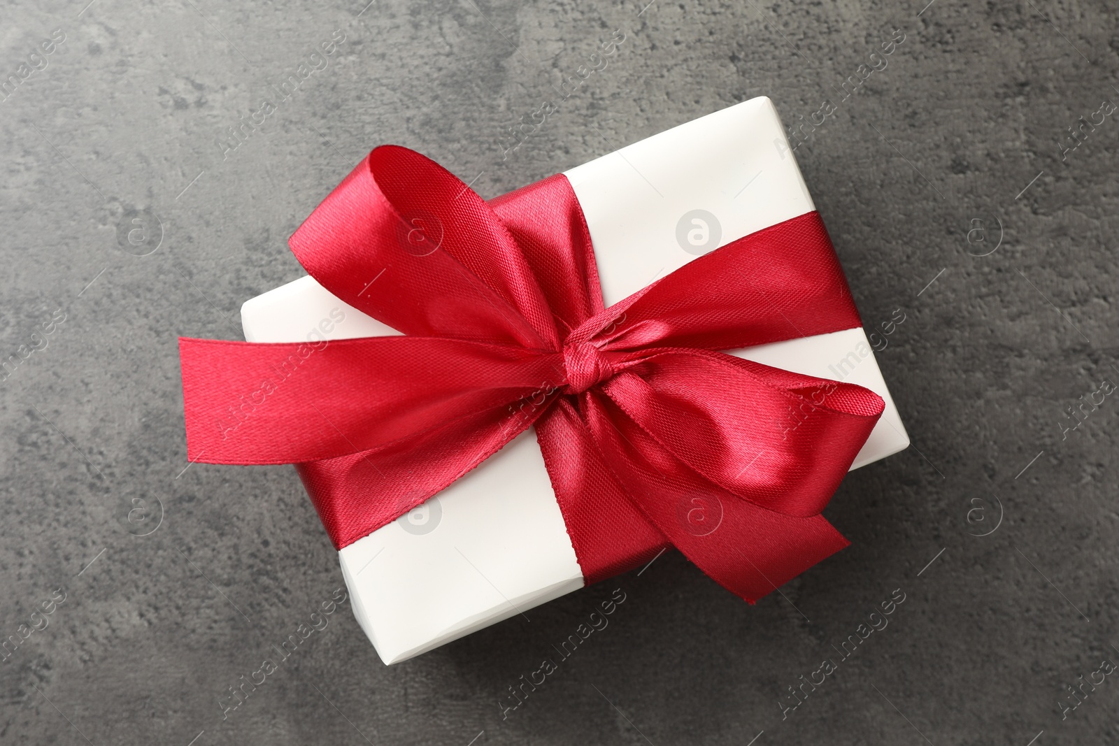 Photo of Gift box with bow on grey table, top view