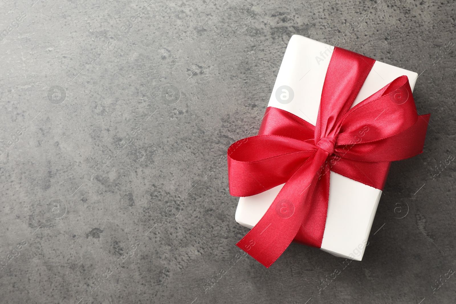 Photo of Gift box with bow on grey table, top view. Space for text