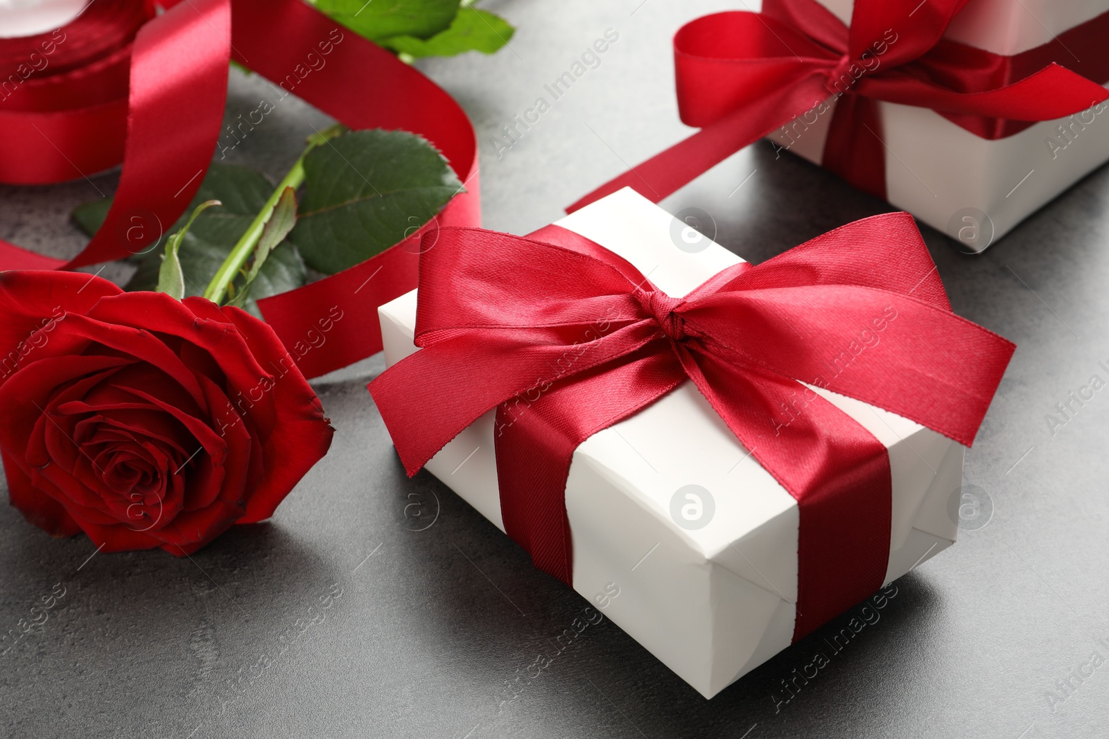 Photo of Gift boxes with bows and rose on grey table