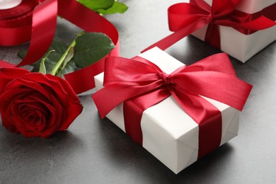 Photo of Gift boxes with bows and rose on grey table