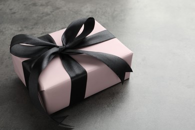 Gift box with bow on grey table. Space for text