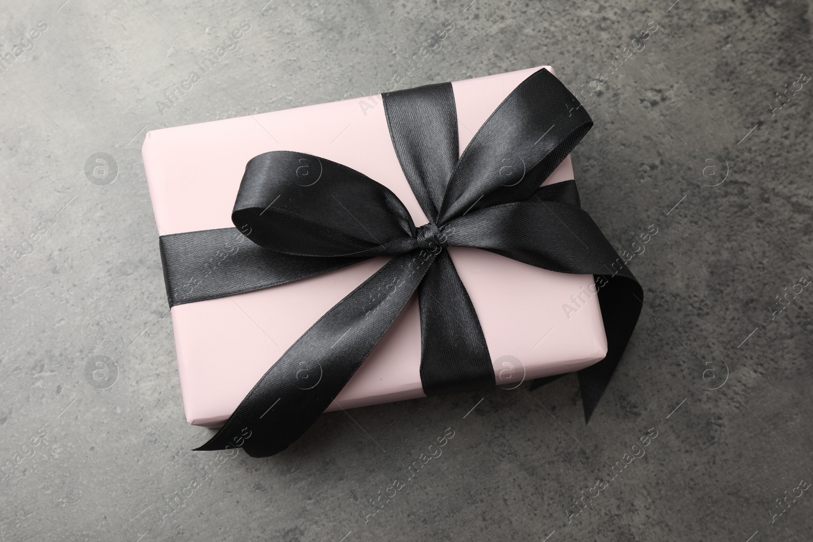 Photo of Gift box with bow on grey table, top view