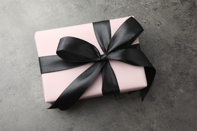 Gift box with bow on grey table, top view