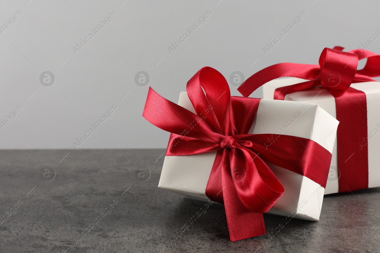 Photo of Gift boxes with bows on grey table, space for text