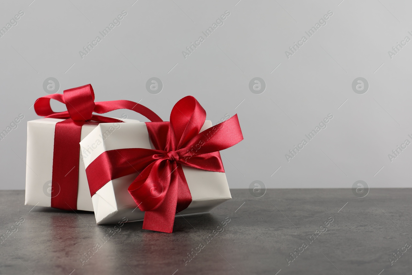 Photo of Gift boxes with bows on grey table, space for text